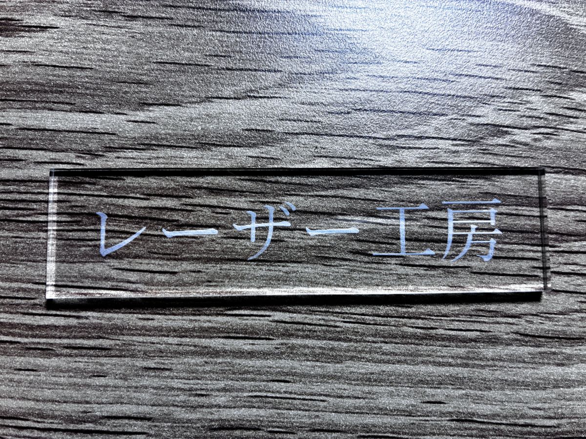 透明アクリルに彫刻した「レーザー工房」の文字。すりガラス状に白く浮かび上がっている